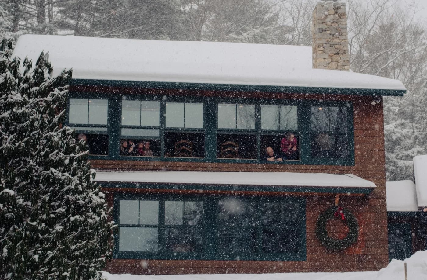 Family watching from the windows of the snowy Sunapee house on the proposal day