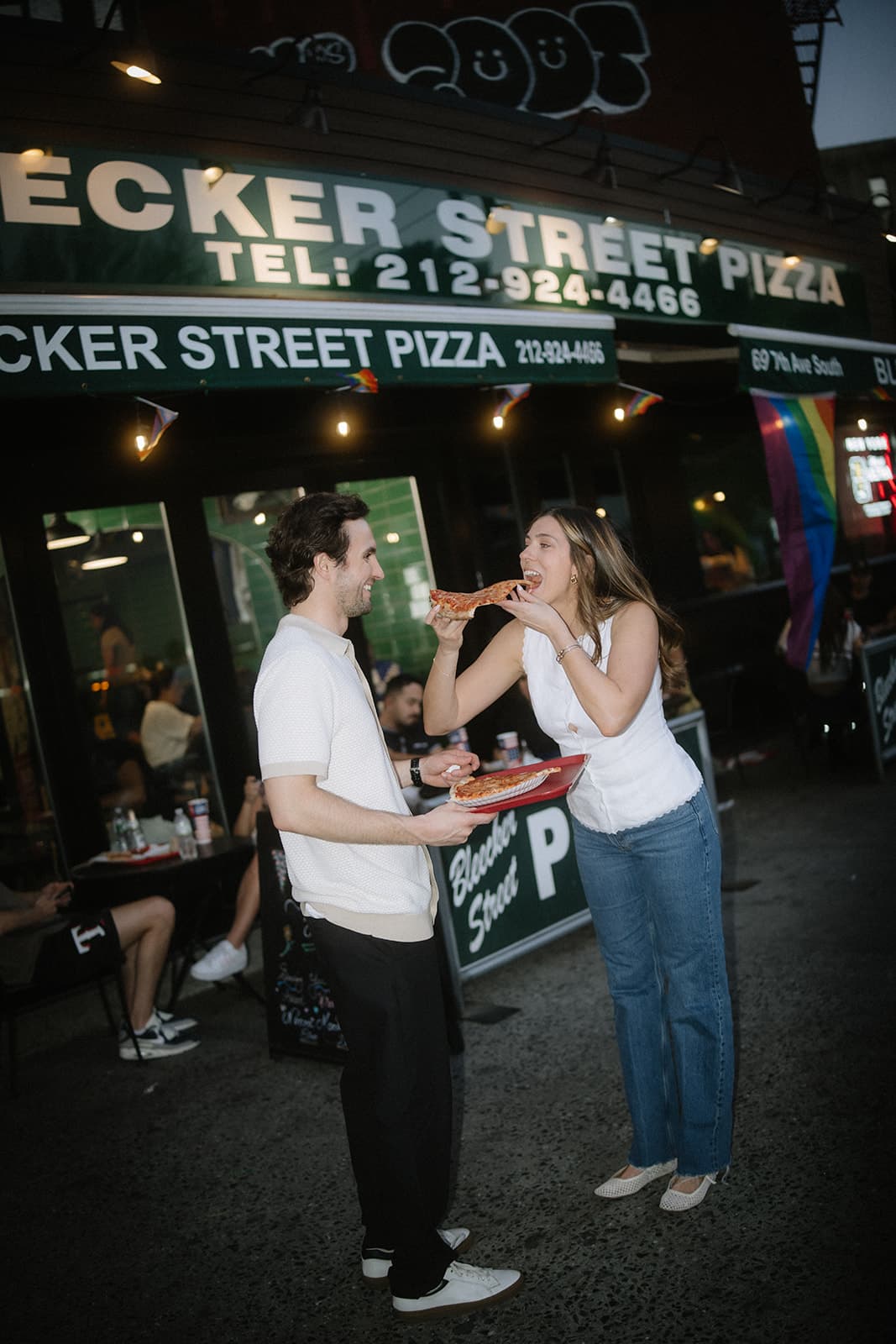 Rachel and Hugh sharing pizza outside Bleecker Street Pizza